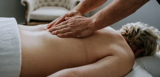 Hands applying pressure to the upper back during massage