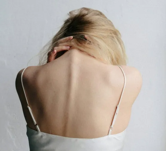 Woman holding her neck and shoulder